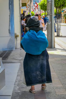 Otavalo şehir sGeçerli kaldırımda yürüyen yerli kadın arkadan görünüm