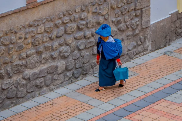 COTACACHI, ECUADOR, 06 DE NOVIEMBRE DE 2018: Mujer no identificada vistiendo ropa indígena y bufanda azul y sosteniendo una bolsa azul en su mano caminando por las calles de Cotacachi — Foto de Stock