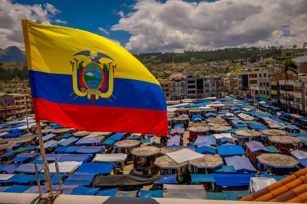 OTAVALO, ECUADOR, NOVEMBER 06, 2018: Beautiful Ecuadorian flags waving in a gorgeous sunny day with huts located in the street market in Otavalo with a mountain behind in Otavalo — Stock Photo, Image