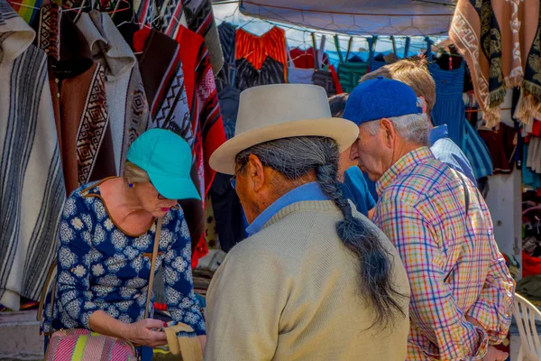 OTAVALO, ECUADOR, 06 DE NOVIEMBRE DE 2018: Turistas comprando artesanías en un mercado callejero ubicado en la ciudad de Otavalo — Foto de Stock