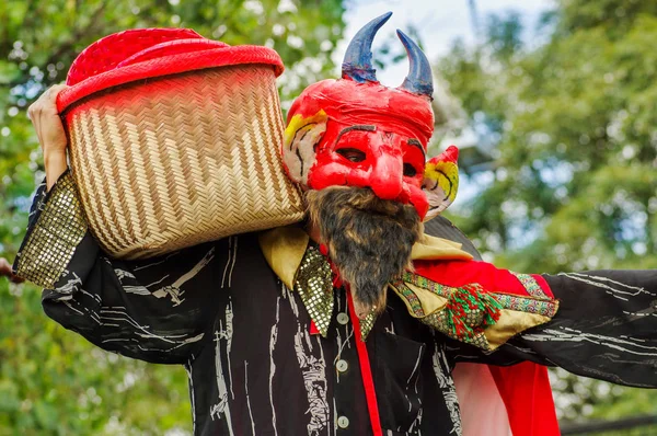 Quito, Equador - 03 de setembro de 2018: Close up de homem não identificado usando uma máscara de diabo, e segurando em seus ombros uma cesta e participando da Diablada, celebração popular da cidade — Fotografia de Stock