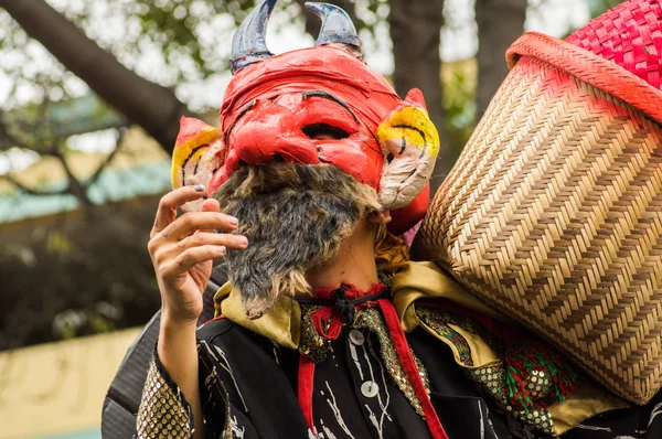 Quito, Ecuador - September, 03, 2018: Close up of unidentified man wearing a devil mask, and holding in his shoulders a basketand and participating in the Diablada, popular town celebration — Stock Photo, Image