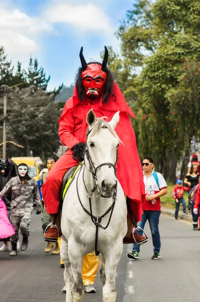 Quito, Ecuador - 03 de septiembre de 2018: Un hombre no identificado con una máscara de demonio y vestido de diablo en la diablada montando un caballo blanco —  Fotos de Stock