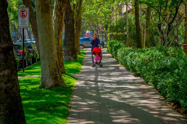 SANTIAGO, CHILE - 13 DE SEPTIEMBRE DE 2018: Vista al aire libre de una mujer con un carro de bebé caminando en un parque ubicado en la ciudad de Santiago de Chile durante un hermoso día soleado —  Fotos de Stock