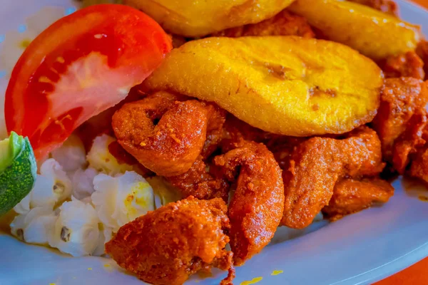 Close up of delicious hornado, ecuadorian traditional typical andean food served with corn, potato, sweet plantain, salad, avocado in a white plate over a wooden table — Stock Photo, Image