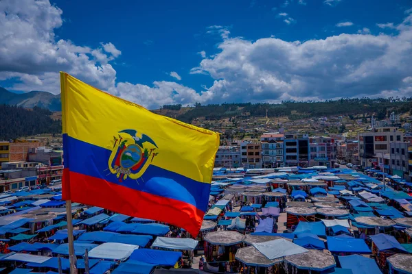 OTAVALO, ECUADOR, NOVEMBER 06, 2018: Beautiful Ecuadorian flags waving in a gorgeous sunny day with huts located in the street market in Otavalo with a mountain behind in Otavalo — Stock Photo, Image