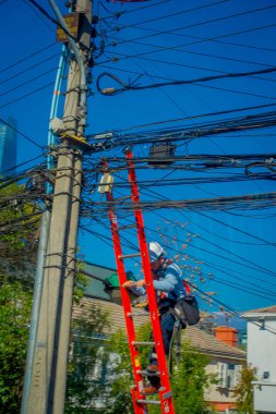 Santiago, Şili - 16 Ekim 2018: bir güzel güneşli gün ve mavi gökyüzü Chile Santiago şehir içinde elektrik bir sorunu çözmek için bir merdiven kullanan kimliği belirsiz adam