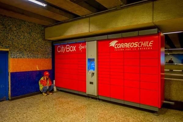 SANTIAGO, CHILE - 16 DE OCTUBRE DE 2018: Vista interior del hombre sentado en el suelo usando su teléfono celular cerca de la urna de correos de chile en la estación de metro en el centro de la ciudad —  Fotos de Stock