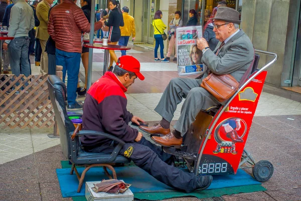 SANTIAGO, CHILE - 16 DE OCTUBRE DE 2018: Vista al aire libre de una multitud de personas caminando en la acera cerca de un hombre sentado en una silla limpiándose los zapatos en Santiago de Chile —  Fotos de Stock