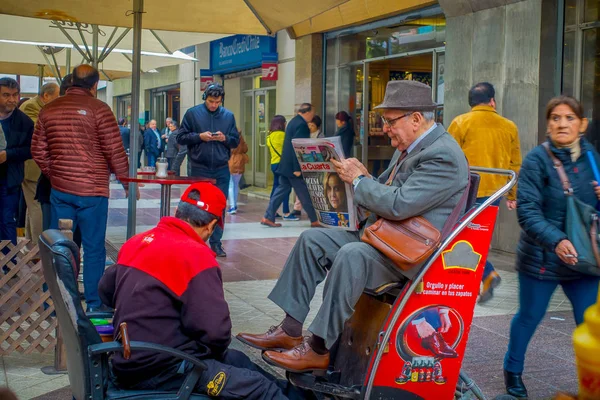 SANTIAGO, CHILE - OUTUBRO 16, 2018: Vista ao ar livre da multidão de pessoas andando na calçada perto de um homem sentado em uma cadeira limpando seus sapatos em Santiago, Chile — Fotografia de Stock