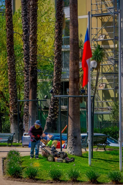 SANTIAGO DE CHILE, CHILE - 16 DE OCTUBRE DE 2018: Vista al aire libre del joven jardinero cortando la hierba de un parque usando una máquina, ubicada en la ciudad de Santiago de Chile —  Fotos de Stock