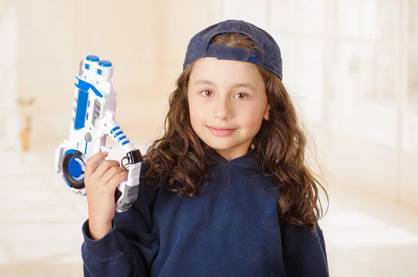 Felice bambina tenendo una pistola tra le mani e indossando vestiti ragazzo — Foto Stock