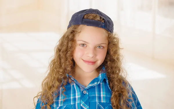 Portret van mooi krullend meisje dragen jongen kleding blauw t-shirt en een hoed — Stockfoto