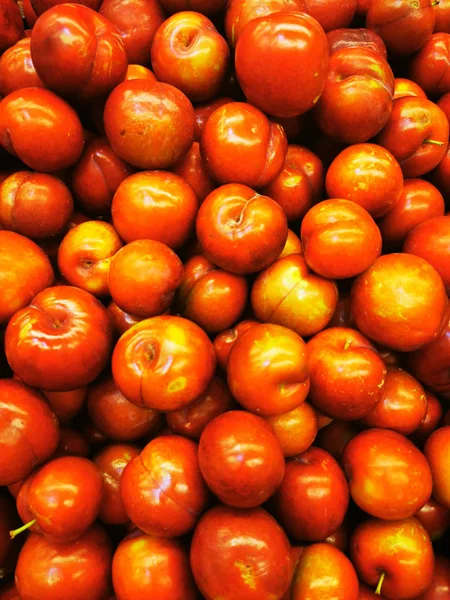 Ripe red greengages in a pile on a market. — Stock Photo, Image