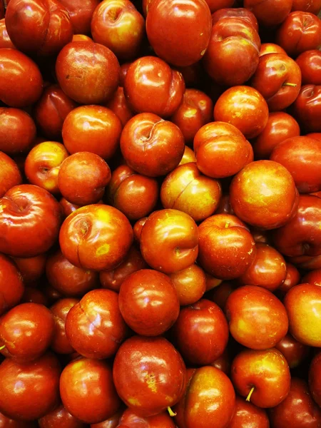 Rijpe rode greengages in een stapel op een markt. — Stockfoto