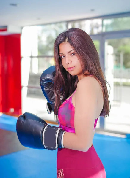 Donna sportiva con capelli scuri in guanti sportivi e outfit viola per la boxe in palestra . — Foto Stock