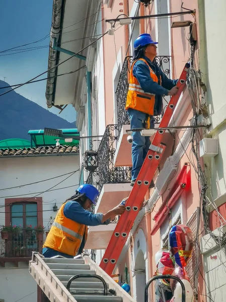 Quito, ECUADOR - 02 de outubro de 2019: Eletricistas estão subindo em postes elétricos para instalar e reparar linhas de energia — Fotografia de Stock