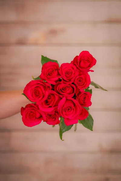 Vrouwen hand met een boeket van Hot Explorer rozen verscheidenheid, studio schot. — Stockfoto