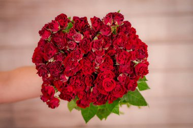 Kadınlar ellerinde bir buket Kelebek Sansasyon Gülleri çeşidi, stüdyo çekimi.