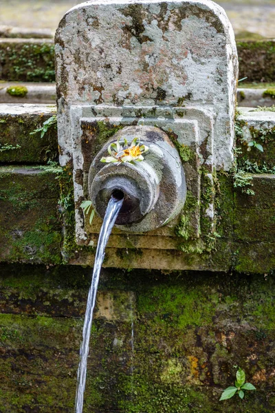 Water spout with canang sari at Gunung Kawi, temple and funerary complex in Tampaksiring, Bali, Indonesia.