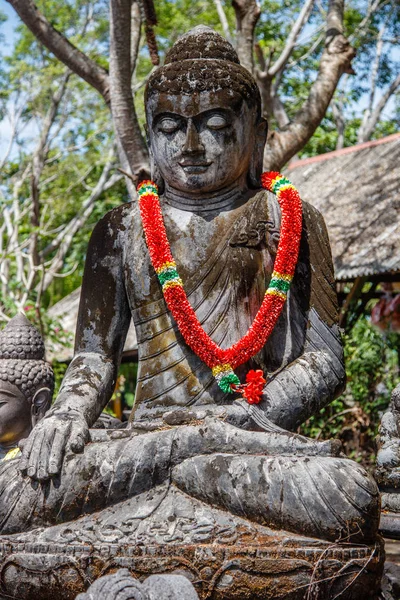 Stone statue of Sitting Buddha under the tree, Bali, Indonesia. Vertical image.