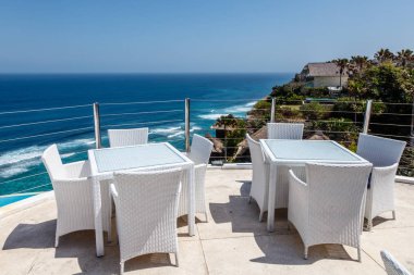 Beyaz masa ve sandalyeler okyanus ile bir açık cliff kafede görüntülemek, Ungasan, Bali, Endonezya.