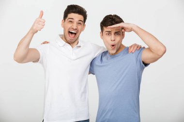Fotoğraf iki erkek arkadaş 30'lu rahat t-shirt ve sarılma ve beyaz arka plan üzerinde izole gülümseme ile kameraya poz kot giyen