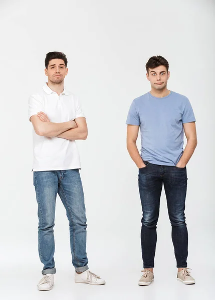 Volledige Lengte Portret Van Twee Verwarde Jonge Mannen Kijken Camera — Stockfoto