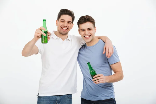 ビール瓶を押しながら白背景に分離カメラ目線を祝う つの幸せな若い男性の肖像画 — ストック写真
