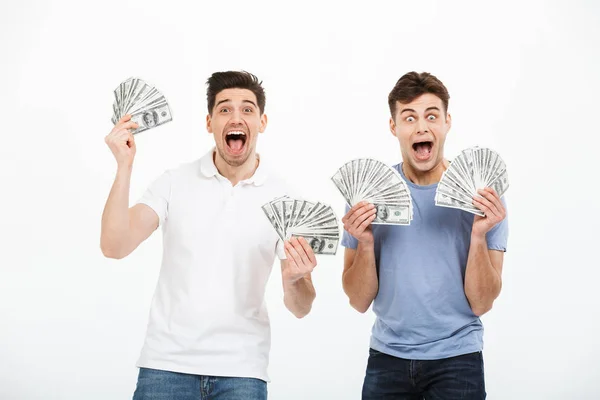 Retrato Dos Jóvenes Satisfechos Mostrando Billetes Dinero Celebrando Éxito Aislado —  Fotos de Stock