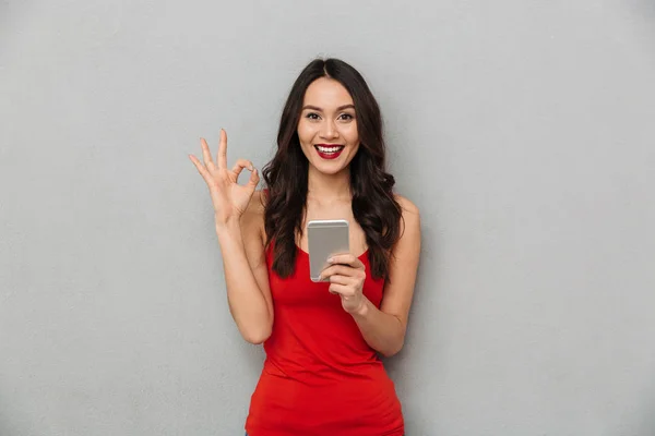 Happy Brunette Woman Casual Clothes Holding Smartphone Showing Sign While — Stock Photo, Image