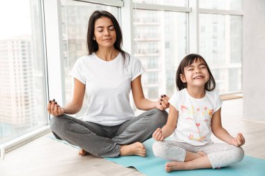 Huzurlu anne ve küçük kızı evde lotus poz mat ve iş yoga mudra jest ile parmak üzerinde oturan meditasyon