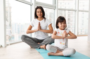 Güzel anne ve çocuk evde oturup bağdaş palms birlikte mat ve iş yoga jestle üzerinde meditasyon