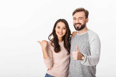 Neşeli genç seven beyaz duvar arka plan üzerinde izole çift görüntüsü. Kamera olun başparmak yukarı dönük arıyorum.