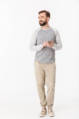 Yakışıklı genç adamın cep telefonu bir kenara bakarak arka plan beyaz duvar sohbet üzerinde izole fotoğraf.