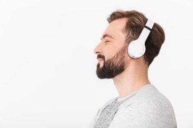 Kulaklık ile müzik dinleme beyaz duvar arka plan üzerinde izole yakışıklı genç görüntü.