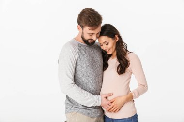 Beyaz arka plan duvardan izole hamile kadını ayakta neşeli genç adam fotoğrafı. Bir kenara arıyorsunuz.