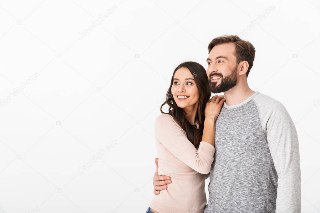 Image of happy young loving couple isolated over white wall background. Looking aside.