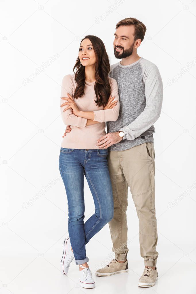 Image of happy young loving couple isolated over white wall background. Looking aside.