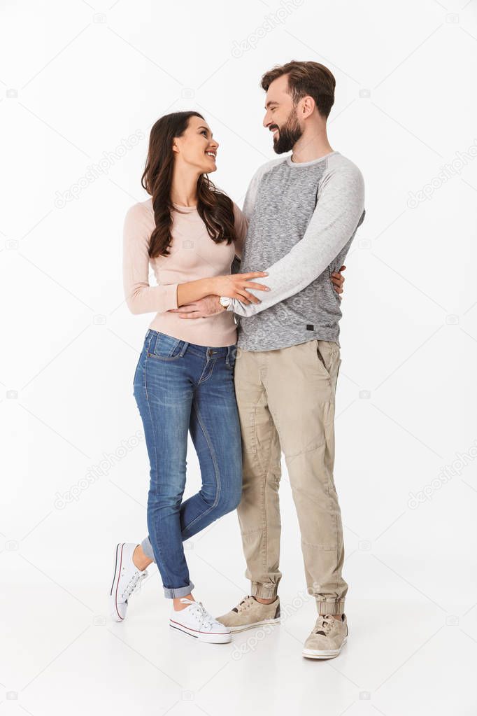 Image of happy young loving couple isolated over white wall background. Looking at each other.