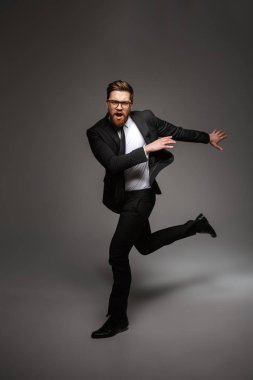 Yakışıklı bir genç işadamı portresi tam uzunlukta atlama gri arka plan üzerinde izole ederken takım elbise poz giyinmiş