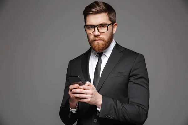 Retrato Jovem Empresário Confiante Vestido Terno Segurando Telefone Celular Isolado — Fotografia de Stock