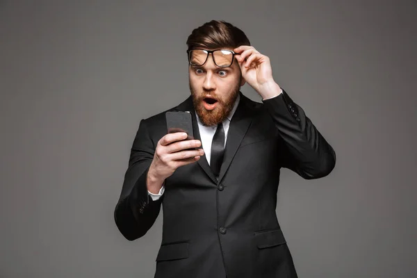 Retrato Joven Empresario Sorprendido Vestido Traje Mirando Teléfono Móvil Aislado —  Fotos de Stock