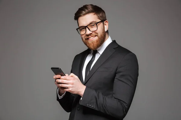Portrait Happy Young Businessman Earphones Holding Mobile Phone Isolated Gray — Stock Photo, Image