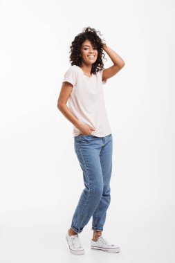 Kot pantolon ve t-shirt samimi bir gülümseme ve beyaz arka plan üzerinde izole cep elinde kamera poz giyen güzel Amerikalı kadın portresi tam uzunlukta