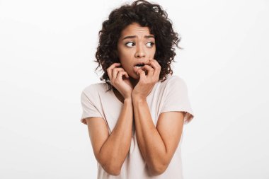 Amerikan kadın 20'li yaşlarda tırnak ısırma ve beyaz arka plan üzerinde izole güvenli olmayan ve korkmuş hissediyor temel t-shirt fotoğrafı