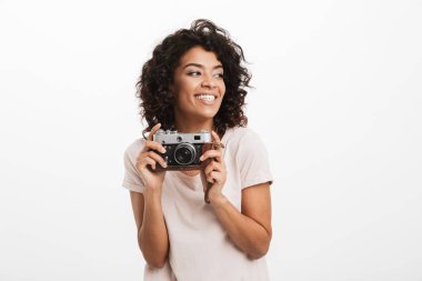Fotoğraf makinesi ve seyir uzağa beyaz arka plan üzerinde izole tutan bir gülümseyen genç afro Amerikan kadın portresi
