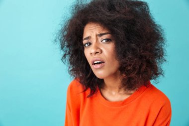 Renkli görüntü closeup kırmızı gömlek izole mavi arka plan üzerinde tereddüt bakışları ile kamera seyir içinde şaşkın kadın