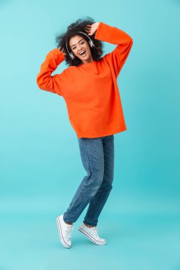 Tam uzunlukta içerik kadın rahat Jeans kablosuz kulaklık ile müzik dinlemek çok renkli fotoğrafı üzerinde mavi arka plan izole