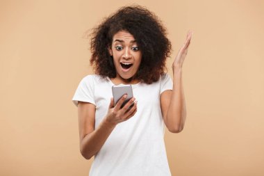 Cep telefonu bej renkli arka plan üzerinde izole bakarak bir sürpriz Afrika kadın portresi
